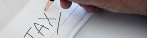 una mano che ha scritto tax su un foglio di carta